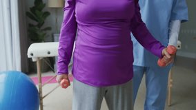 Physical therapist placing hand and guiding patient lifting dumbbell in arc for shoulder strength. Rehabilitation, physiotherapy, fitness, wellness, support, empowerment, education - Powered by Shutterstock - Get 15% off with code: PIKWIZARD15