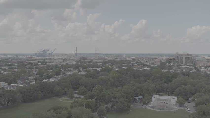 Cinematic 4K aerial drone footage showcasing a lush park surrounded by trees, residential housing, and nearby building structures in Savannah, Georgia. The sweeping aerial view captures the balance be
