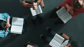 Top down view of prayers reading bible with cross on the laps while making folded hands. Aerial view of diverse people praying to god with faith, trust and hope. and sitting in circle. Symposium. - Powered by Shutterstock - Get 15% off with code: PIKWIZARD15