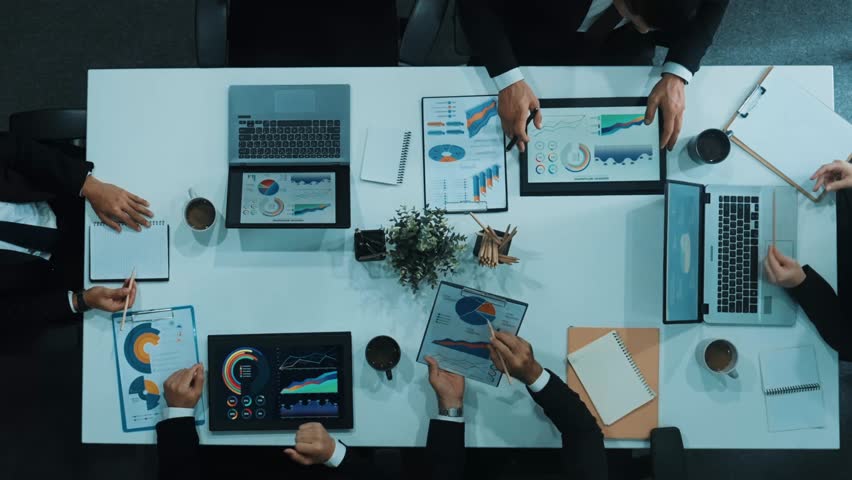 Top down aerial view of smart business woman handing out financial document to diverse team while discuss or brainstorm about marketing strategy with investment chart display on tablet. Directorate. - Powered by Shutterstock - Get 15% off with code: PIKWIZARD15
