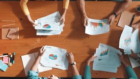 Top down view of start up business team holding paper while discussing about financial idea. Aerial view of smart diverse people brainstorming idea while looking at stock market statistic. Symposium. - Powered by Shutterstock - Get 15% off with code: PIKWIZARD15