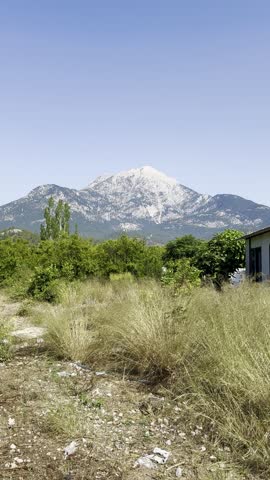 Mount Tahtali in Tekirovo.Mountain peak with rocky slopes under clear blue sky, view through dry grass and green forest in summer.High quality 4k footage