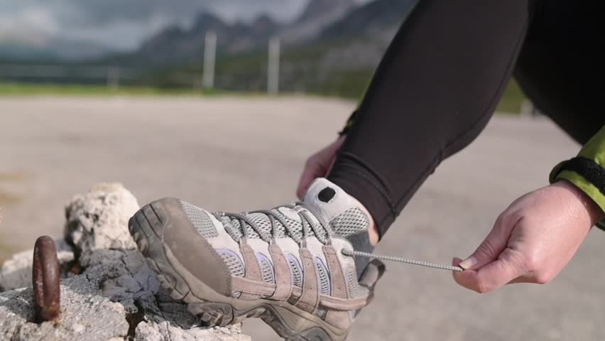 Close-up of hands tying hiking boots on rocky terrain in the Dolomitines Alpes