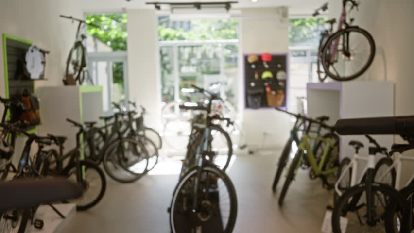 Blurry bike shop interior showcasing various bicycles on display with natural light through large windows, creating a bright and inviting retail atmosphere.