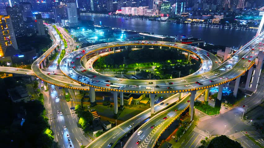 Aerial view of the illuminated Nanpu Bridge at night, a multi-level highway interchange with heavy traffic, connecting urban districts of Shanghai, China.