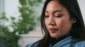 Smiling Asian woman talking to Artificial Intelligence Voice Assistant on smartphone, using Ai chat bot, ai agent agent for helping work, analysis data while sitting on couch in living room at home. - Powered by Shutterstock - Get 15% off with code: PIKWIZARD15