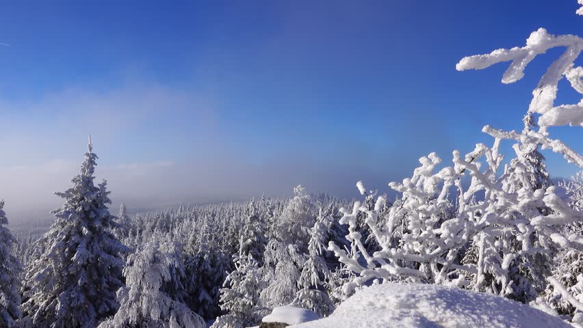 view of snowy mountains under bright sun with clouds floating. winter landscape