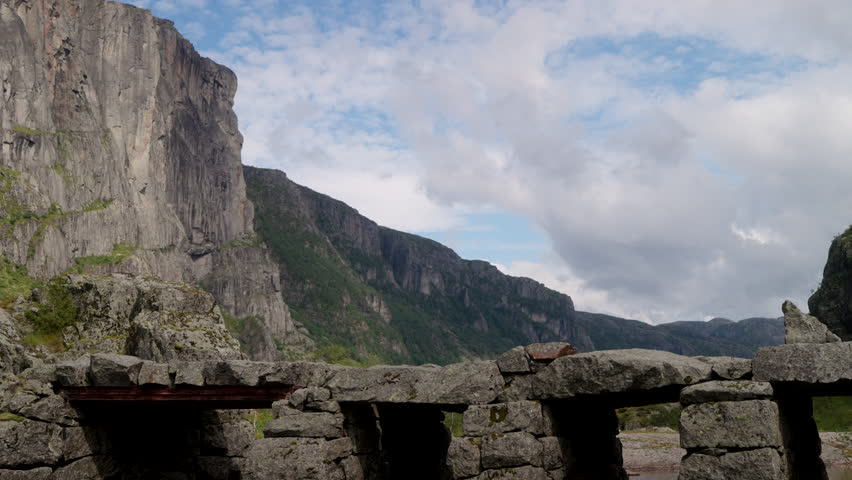 Hiking couple with dog cross stone bridge over river in rugged Norway landscape