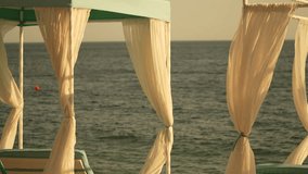 Canopy, sea, curtains on a beach with light fabric flowing, creating a peaceful vacation scene - Powered by Shutterstock - Get 15% off with code: PIKWIZARD15