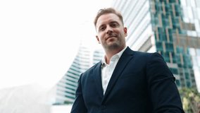 Low angle camera of businessman looking at watch to remind about time. Smart caucasian businessman checking time for being on time in important appointment or meeting with modern skyscraper. Urbane. - Powered by Shutterstock - Get 15% off with code: PIKWIZARD15