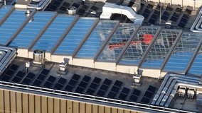 Contemporary building rooftop in Vilnius, Lithuania, featuring glass skylights, ventilation ducts, and solar panels under evening sunlight. - Powered by Shutterstock - Get 15% off with code: PIKWIZARD15