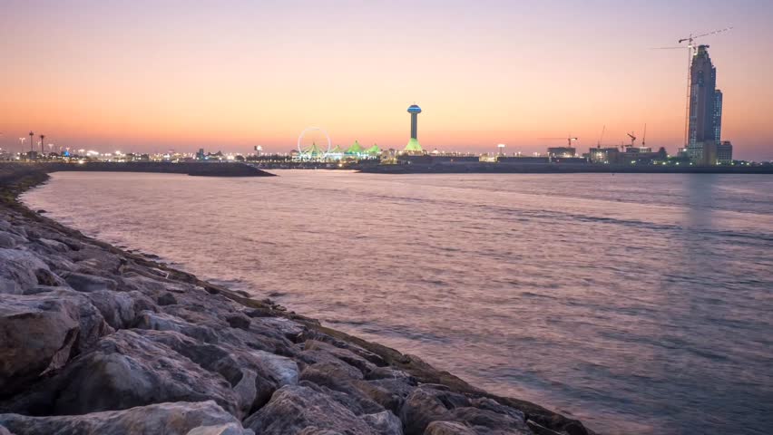 A captivating day-to-night time-lapse of the Abu Dhabi skyline from across the water. The scene transforms from a colorful sunset into a dark night sky, brilliantly  by the city