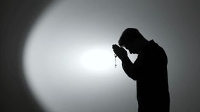 Man silhouette praying rosary for faith and devotion. spirituality, christianity - Powered by Shutterstock - Get 15% off with code: PIKWIZARD15