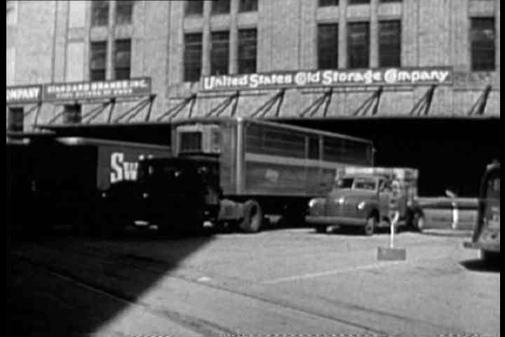1930s - A truck passing an old warehouse.