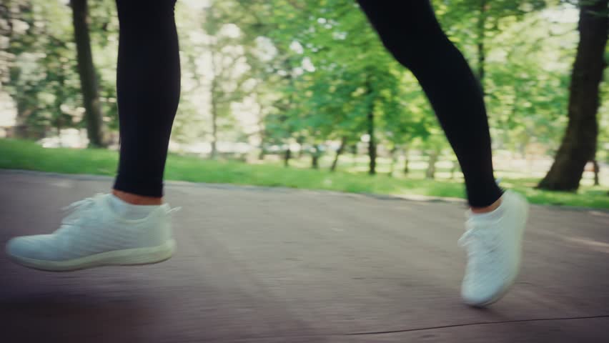 Close-up of female legs running on a park pathway