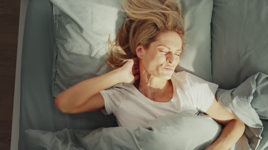Woman waking up with neck pain in morning bed