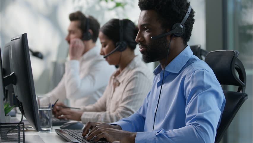 Multinational team African male callcenter operators thumbs up headset smiling office computer support female Indian coworker typing customer service happy Caucasian colleague job call center business - Powered by Shutterstock - Get 15% off with code: PIKWIZARD15