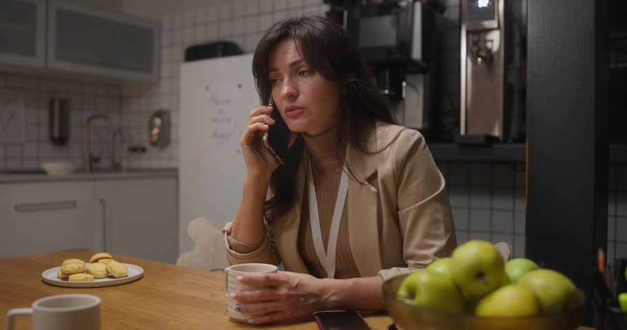 Worried businesswoman talking on phone during office break stressed expression emotional conversation workplace anxiety coffee time corporate pressure moment