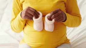 Young African American woman cherishes baby shoes while expecting at home - Powered by Shutterstock - Get 15% off with code: PIKWIZARD15