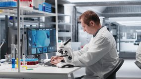 Male science expert operates with microscope and laboratory tray, studying chemical and biological samples for medical research. Magnified observation of DNA in modern science. Camera B. - Powered by Shutterstock - Get 15% off with code: PIKWIZARD15