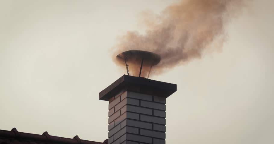 Rural house roof chimney, thick smoke coming from burning wood and coal. Air pollution from bad heating practices is common in Eastern Europe countryside