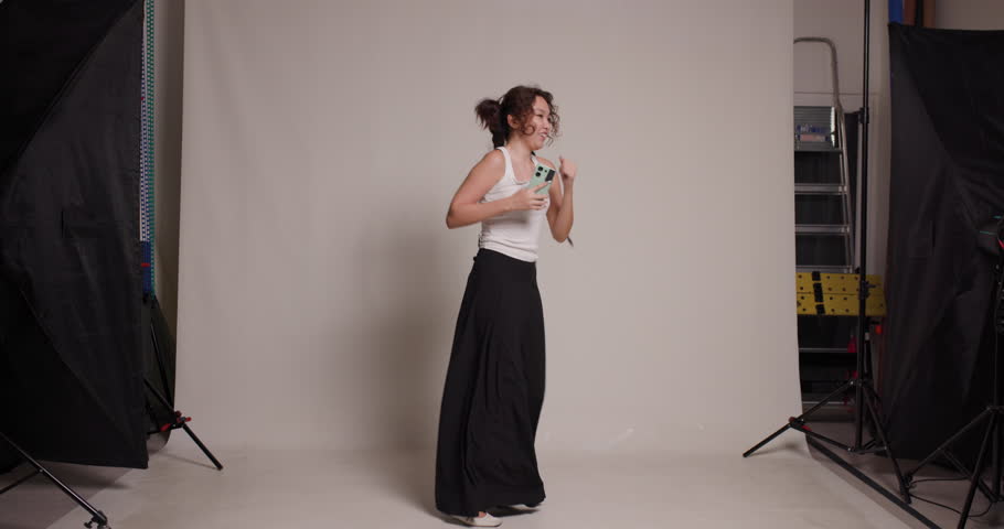 A dynamic image capturing a young Kazakh woman as she practices dance steps in a professional studio, under soft studio lighting.