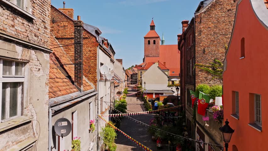 Drone establishing view of narrow history street, church tower, Grudziadz Poland