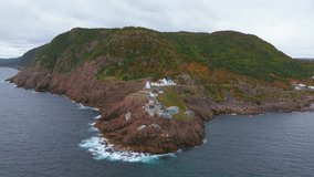 Cinematic drone footage captures Fort Amherst’s quiet inlet and sloping hills dotted with pastel homes, where rocky terraces meet a calm harbor and waves gently break along the shoreline. - Powered by Shutterstock - Get 15% off with code: PIKWIZARD15