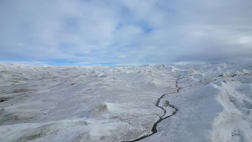 Aerial flyover: Vast textured ice glacier extends to distant horizon