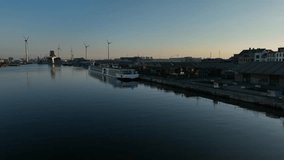 Antwerp industrial harbor at sunset with cruise ships, warehouses, and wind turbines, camera pan right across the calm river under evening light - Powered by Shutterstock - Get 15% off with code: PIKWIZARD15