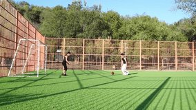 Close action as one player blocks the other attempt to advance red ball near goal. Both wear black, move swiftly over green turf under bright sun. - Powered by Shutterstock - Get 15% off with code: PIKWIZARD15