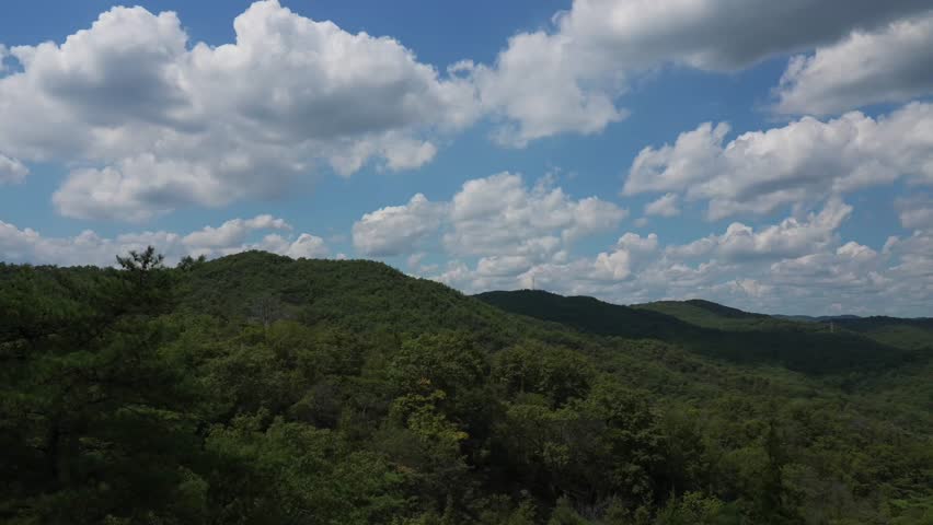 From the top of Ki Castle, one of Japan's Top 100 Castles, under a blue sky with white clouds, the rolling, lush mountains form a magnificent and vibrant natural landscape.