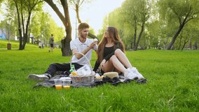 young couple in love sits on blanket on the grass and eats wine and croissants, man and woman relax on picnic in the park - Powered by Shutterstock - Get 15% off with code: PIKWIZARD15
