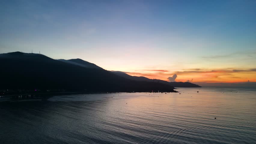 Warm sunlight illuminating son tra mountain's coastal landscape, golden rays casting ethereal glow across serene da nang bay during spectacular dawn moment