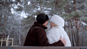 Mature man and woman affectionately embracing while sitting on a bench. Elderly couple enjoying a loving moment together in a snowy forest - Powered by Shutterstock - Get 15% off with code: PIKWIZARD15