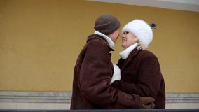 Elegant elderly couple enjoying a romantic date outdoors. A happy man and woman in warm winter coats hugging, talking, and kissing fondly - Powered by Shutterstock - Get 15% off with code: PIKWIZARD15