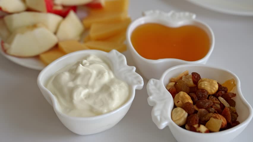 Gather around for a delightful afternoon with fresh apples, cheese, and creamy yogurt. Enjoy tasty nuts and honey, perfect for sharing in a warm atmosphere with friends.