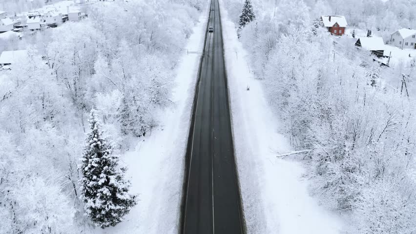 Aerial view of road with cars driving through winter forest with snow. Concept of dangerous driving on slippery and snowy road 