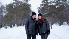 Happy couple holding hands while walking and talking in a beautiful snowy park. Loving man and woman enjoying a romantic date outdoors - Powered by Shutterstock - Get 15% off with code: PIKWIZARD15