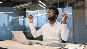 African american businessman meditating with closed eyes during a break at work while sitting at workplace in business office. Calm handsome black man worker practices yoga and feels peace of mind - Powered by Shutterstock - Get 15% off with code: PIKWIZARD15