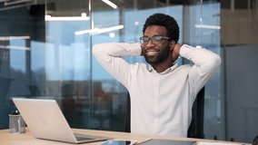 Happy African American businessman finished work on laptop while sitting at desk at workplace in business office. Satisfied black man puts his hands behind his head, leaning back in a chair. Work done - Powered by Shutterstock - Get 15% off with code: PIKWIZARD15