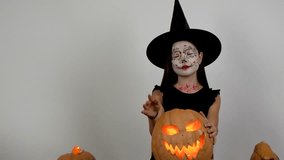 A girl in a witch costume is holding a glowing carved pumpkin - Powered by Shutterstock - Get 15% off with code: PIKWIZARD15