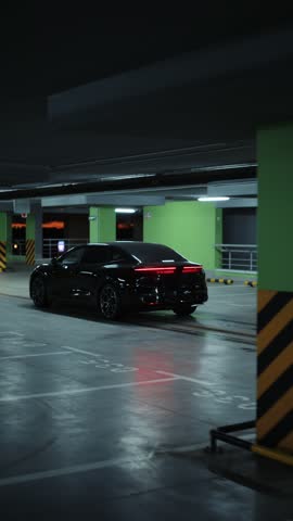 Black electric car driving through underground parking garage