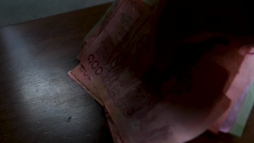 Woman hand holding and examining Vietnamese dong and Thai baht banknotes currency exchange concept travel money spending shopping Southeast Asia financial transactions.