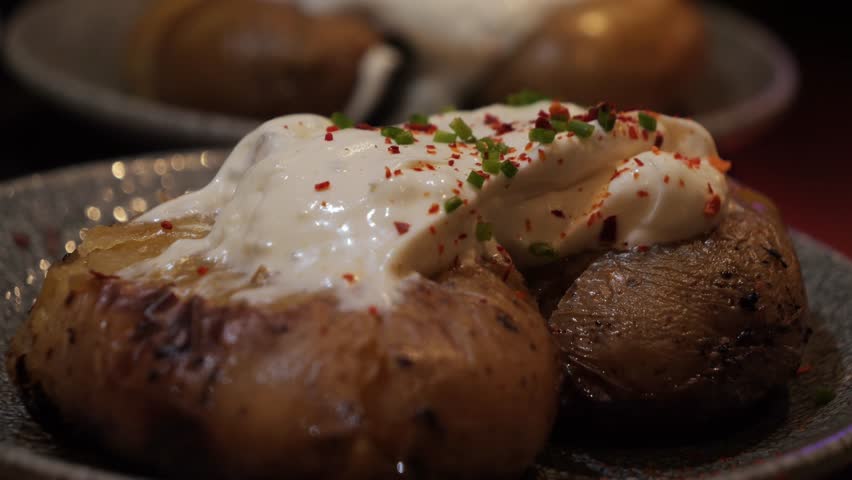 Baked new potatoes in the oven served with garlic cream sauce and herbs and paprika. High quality 4k footage