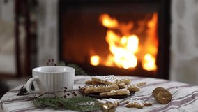 Cozy christmas video. Gingerbread christmas cookies and warm cup of tea, fir branches and ornaments on table on background of burning fireplace. Merry Christmas!  - Powered by Shutterstock - Get 15% off with code: PIKWIZARD15