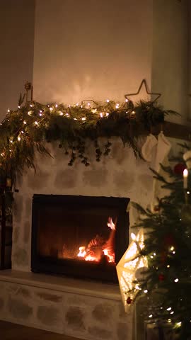 Burning festive decorated fireplace and christmas tree with twinkling lights in living room at night. Merry Christmas and Happy Holidays! Christmas cozy magical eve, vertical video
