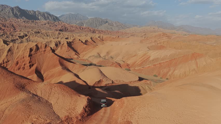 Aerial view of the Huoyun Valley revealing warm, earthy tones of the rugged terrain contrasting with the distant, cool mountain ranges, Huoyun Valley, China.