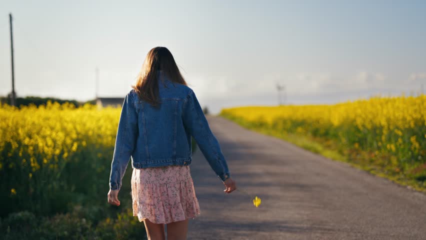Smiling woman strolls through blooming yellow rape fields