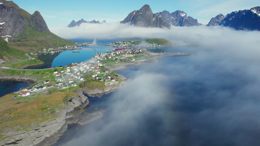 Scenic aerial view of the fishing village of Reine in Norway surrounded by mountains and low clouds